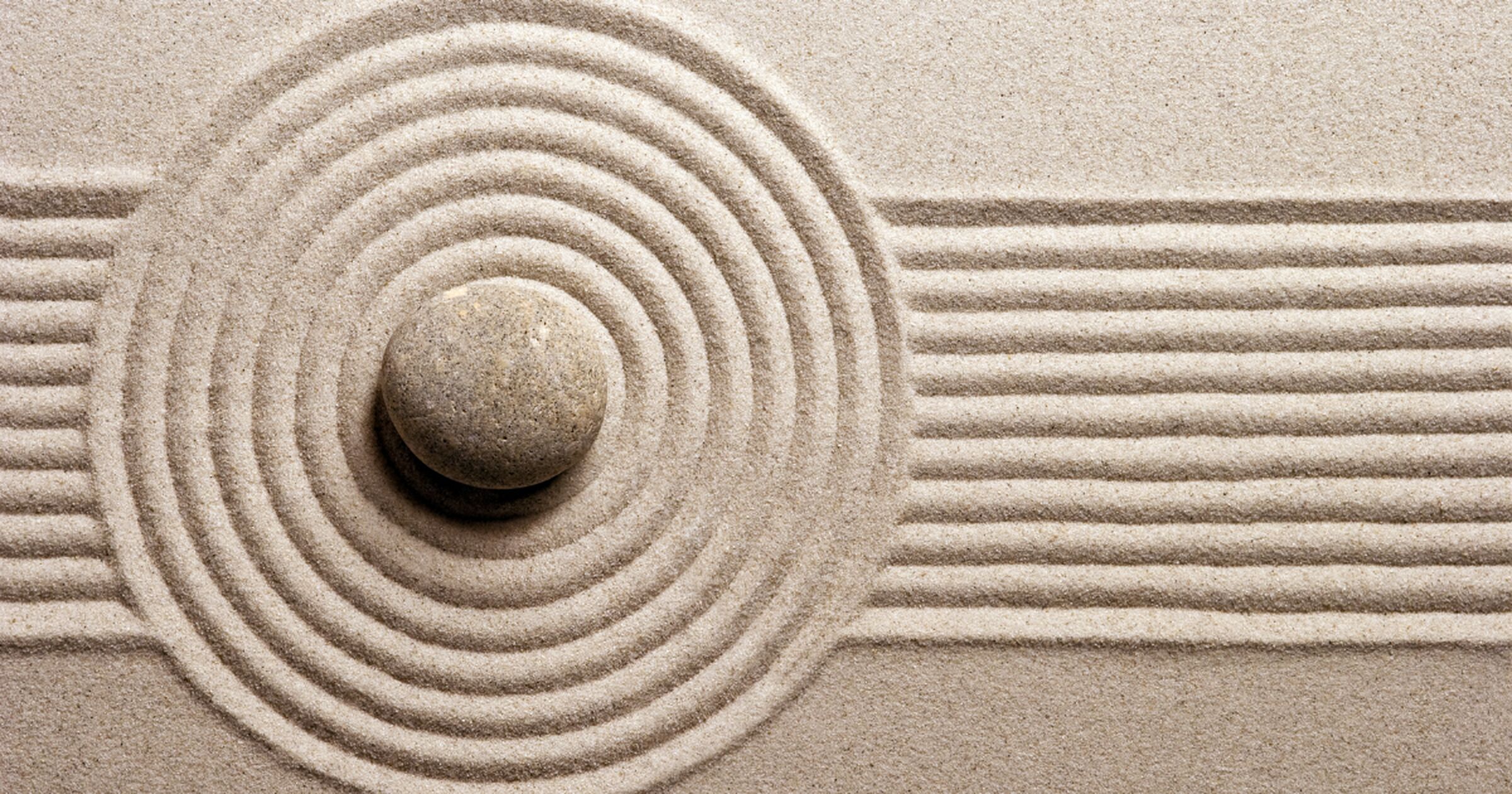 Raked sand ripples around a stone in a Zen garden